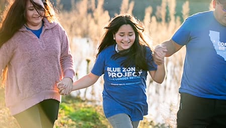 Family holding hands running through the field